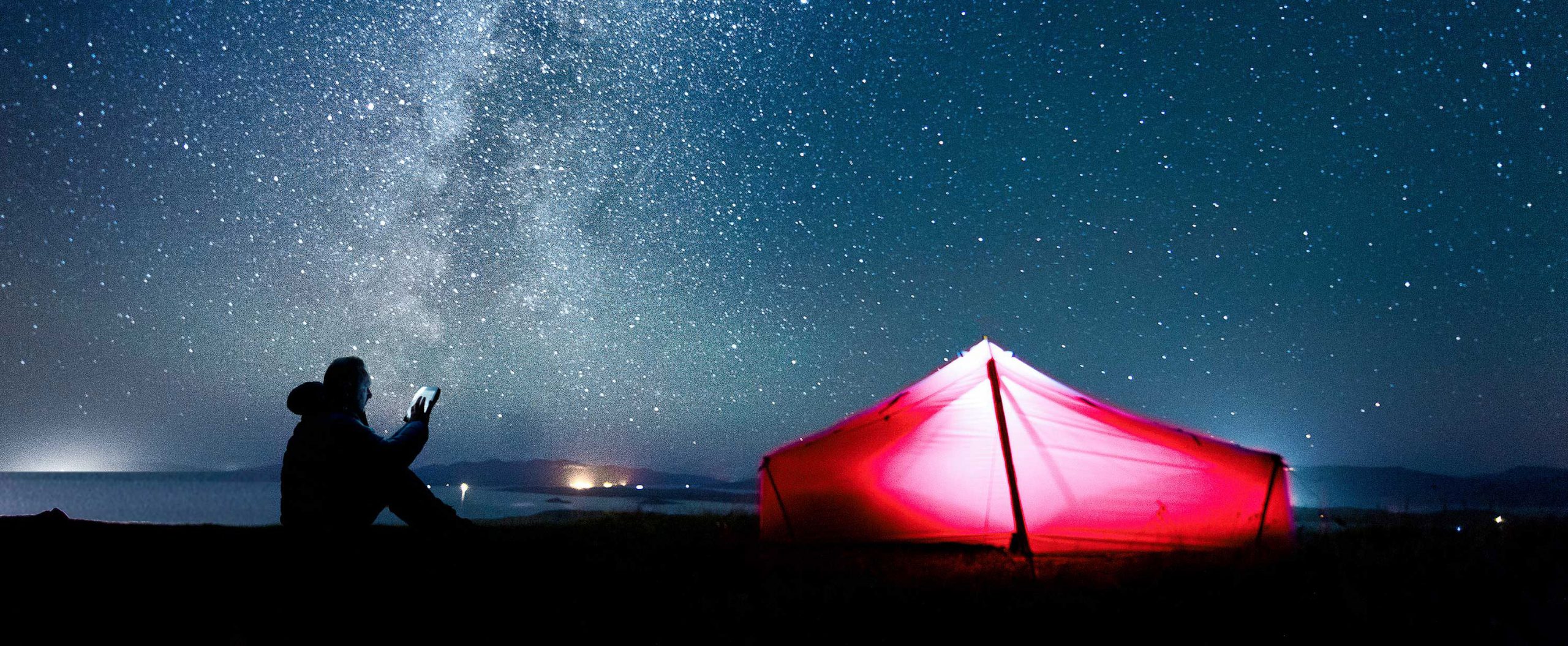 Lit tent against a starry night - camper is using Mojo management software from his device